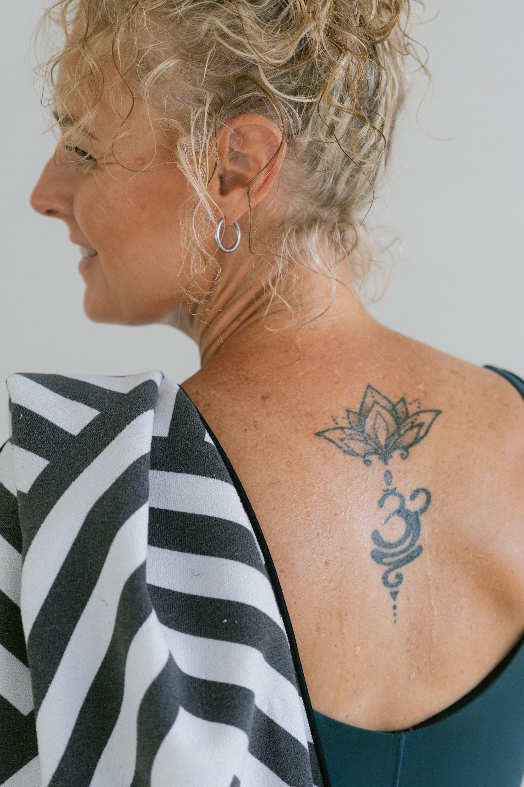 Melanie outside the studio — profile, hair, and lotus tattoo